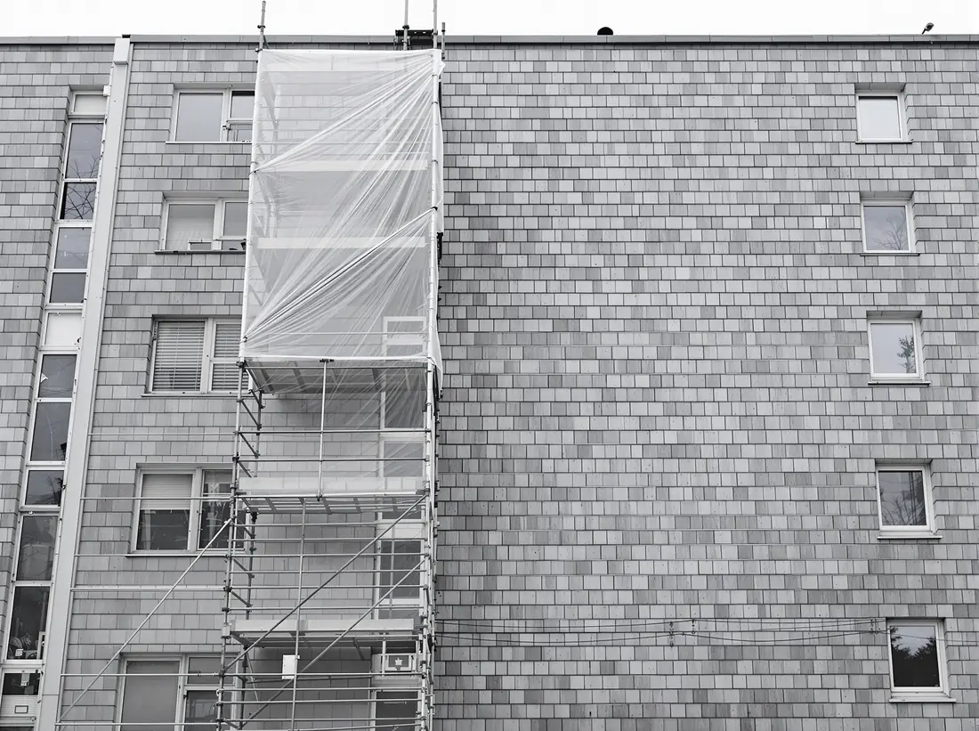Kleinformatige graue Fassadenplatten an einem älteren Wohnhaus